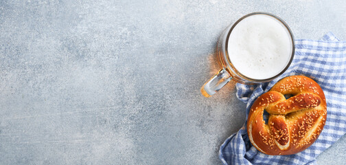 Bavarian pretzels and glass of lager beer. Oktoberfest food menu, traditional salted pretzels on light grey background. Top view with space for text. Oktoberfest theme