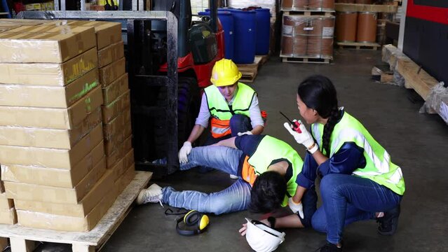 First Aid and safety first. Engineering talking on walki talki radio to employee while his warehouse coworker lying unconscious at industrial factory. Health insurance emergency accident in workplace.