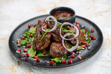 fried kebab in a black plate with salad and pomegranate berries

