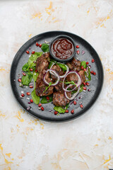 fried shish kebab in a black plate with salad and pomegranate berries vertical photo
