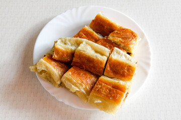Turkish style meat stuffed filo dough borek served kol boregi. Cheese and minced pie are sliced on a marble background. Turkish name: Kol Boregi, kiymali, peynirli su boregi.