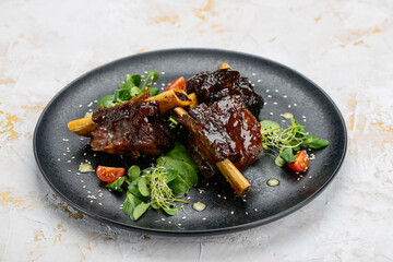 fried ribs in sauce in a black plate
