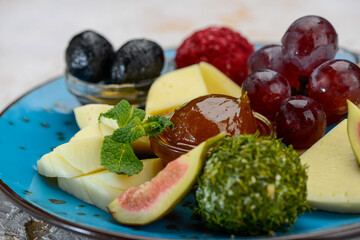 canned fruits and berries with cheese in a blue plate macro photo
