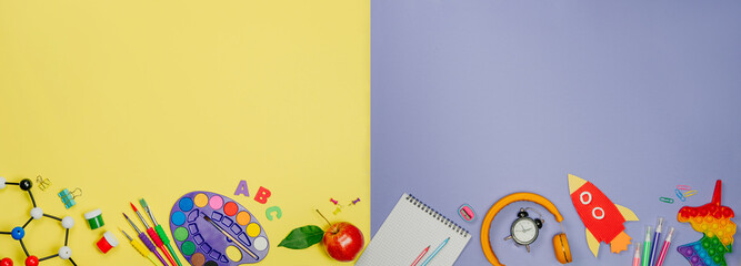 Different school stationery on purple and yellow background with copy space