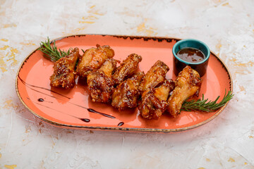 grilled chicken wings sprinkled with sesame seeds in an orange plate
