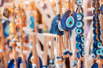 Evil eye turkish bead amulets hanging in souvenir store. Gift and superstitions concept - obrazy, fototapety, plakaty