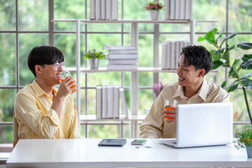 Asian gay couple drinking orange juice together in home,  LGBTQ concept.
