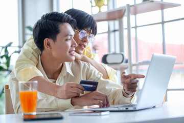 Asian gay couples are using laptop or shopping online with credit card,  LGBTQ concept.