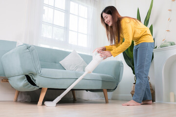 Happy Asian woman using vacuum cleaner dust while cleaning floor at home, Female housekeeper,...