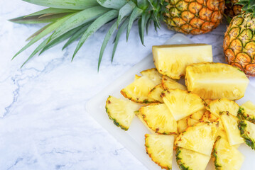 sliced pineapple on cutting board with whole freshly harvested pineapple.