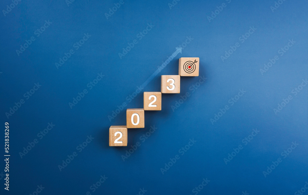 Poster 2023 year numbers on on wooden blocks stack, chart steps with shining rise up arrow to the target ic