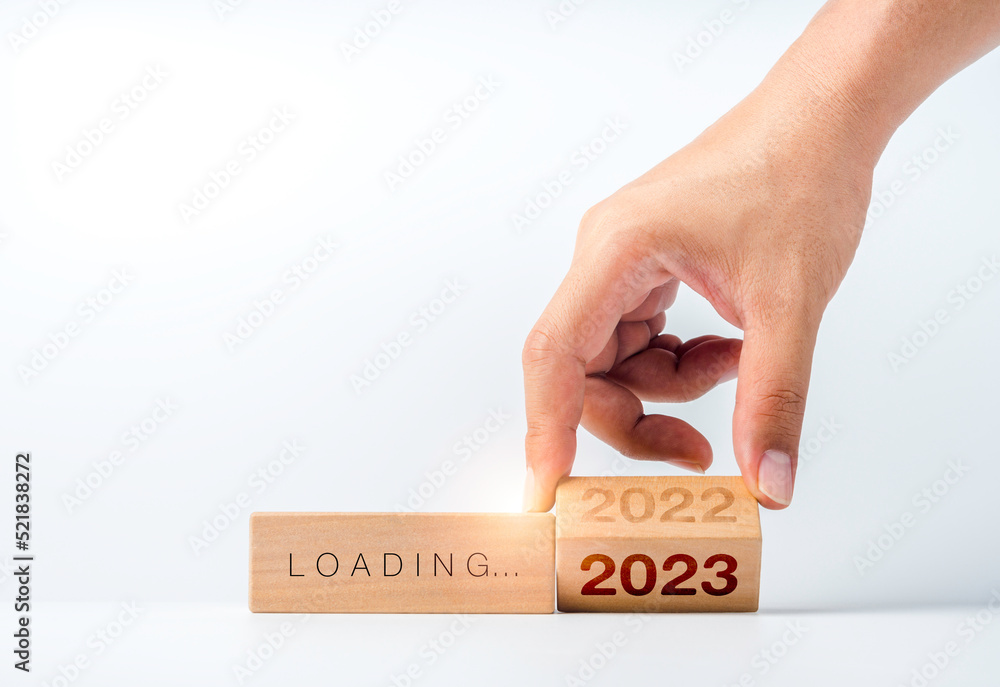 Poster loading to 2023 happy new year. hand flipping the 2022 to 2023 year numbers calendar on wooden cube 