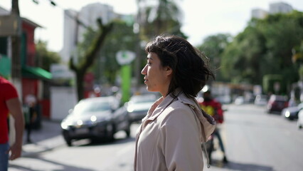 One hispanic woman crossing street. Person crosses crosswalk in urban city