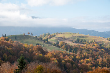 Fototapeta na wymiar carpathian landscape in october. hills and mountain range in warm sunny weather with low clouds in the sky in autumn