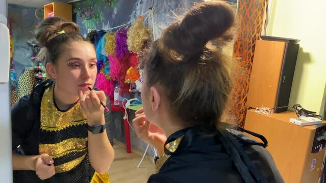 Artist puts makeup in front of mirror for performance before going on stage in dressing room. Actress getting ready for show. Close up.