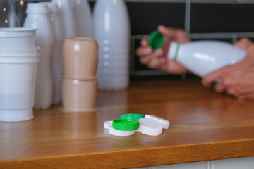 many colored plastic bottle caps on countertop in kitchen on background of person who sorting waste