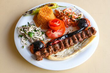 Grilled Turkish Adana, Urfa  Kebab with grilled vegetables, onion and rice on plate. Adana durum .