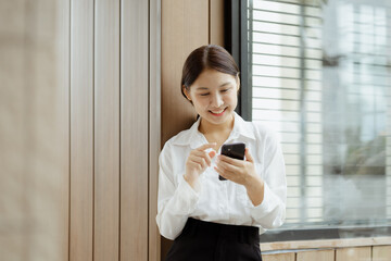 Asian woman using mobile phone, she surfs internet and social media on smartphone, chatting on app with friends. The concept of using technology in communication and the use of the Internet.