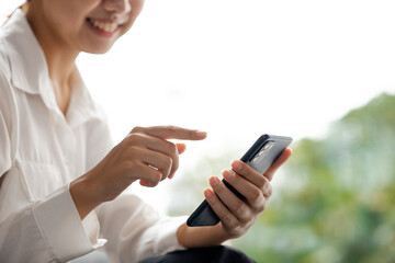 Asian woman using mobile phone, she surfs internet and social media on smartphone, chatting on app with friends. The concept of using technology in communication and the use of the Internet.