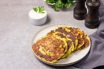 Vegetarian zucchini fritters or courgettes pancakes, served with fresh herbs and sour cream.