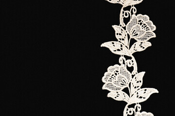White lace with flowers and leaves on black background isolated vertically with copy space