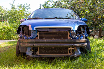 An old car is in the yard. A broken car stands on green grass.