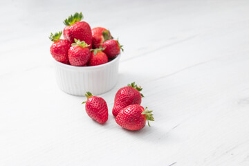 Fresh ripe delicious strawberries in a white bowl on a gray stone background