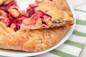 French galette or pie with strawberries and almonds on baking paper on a culinary background top view. Summer homemade sweet pastries