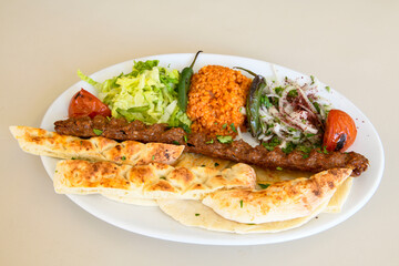 Grilled Turkish Adana, Urfa  Kebab with grilled vegetables, onion and rice on plate. Adana durum.
