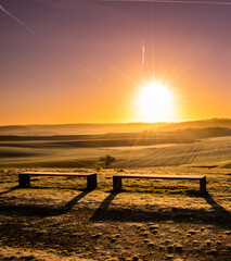 Wooden bench on a green meadow with colorful sunset