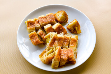 Turkish style meat stuffed filo dough borek served kol boregi. Cheese and minced pie are sliced on a marble background. Turkish name: Kol Boregi, kiymali, peynirli su boregi.