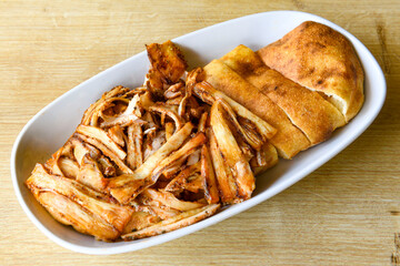 Turkish and Arabic Traditional Ramadan doner kebab with tasty tomato sauce and rice or turkish pilav in white plate on wood table background. ( Pilav ustu doner)