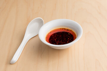 Asian restaurant hot chili sauce with a ceramic spoon