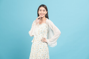 Beautiful young asian woman in white dress with flower pattern isolated on blue background