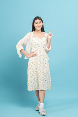 Beautiful young asian woman in white dress with flower pattern isolated on blue background