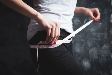 Woman measuring her waist with a measuring tape.