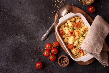 Baked cauliflower cooked with tomatoes and creamy cheese, healthy vegetable meal