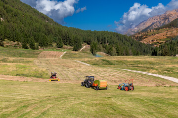 View of alpine meadows with agricultural equipment for haymaking