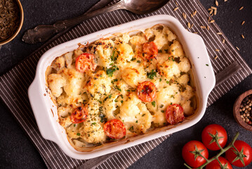 Baked cauliflower cooked with tomatoes and creamy cheese, healthy vegetable meal