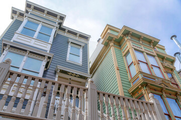 Low angle view of two townhouses with gray and green vinyl lap sidings in San Francisco, CA