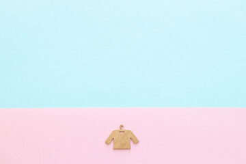 A wooden figure of a clothes hanger on a blue pink background. Shopping concept