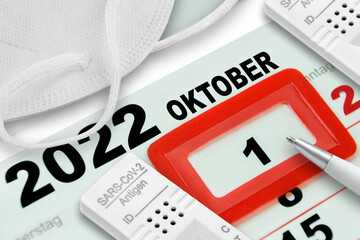 Deutscher Kalender mit Datum 1. Oktober 2022 und Corona Pandemie mit FFP2 Maske