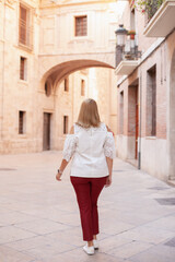 Fototapeta na wymiar Rear view on woman walking in the historic center. Tourism in Europe