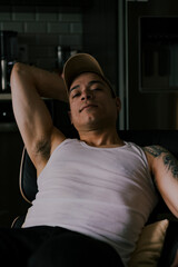 Fototapeta na wymiar Latino american male in a tank top, sitting in a chair and staring at the camera