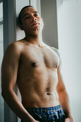 Fototapeta premium Latino male veteran posing in door frame, looking down at the camera while shirtless
