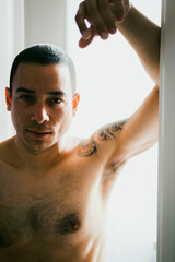 Fototapeta na wymiar Latino male veteran posing in door frame looking at the camera while shirtless