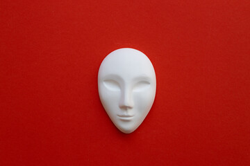Fototapeta na wymiar Ceramic white mask on red background