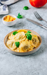 Homemade Pumpkin Ravioli with sauce and bsil on concrete background. Autumn food concept. Selective focus