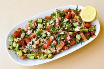 Green salad with arugula, lamb and tomatoes. Healthy vegan dish. Top view at table. Turkish Coban (choban) salata or Shepherds salad, Akdeniz salad in white bowl.