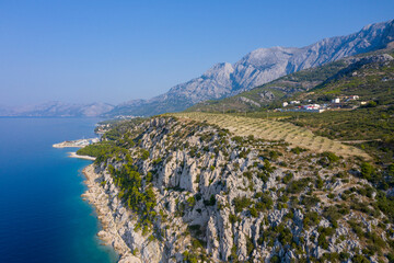 Drone footage. Beautiful nature. Path by the sea. Pine trees over turquoise water. Summer landscape. Mountains, blue Adriatic sea. Wild, romantic beach. Pleasure. Vacation. Relax. Romance.